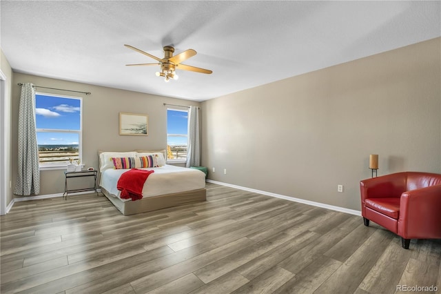 bedroom with baseboards, multiple windows, and wood finished floors