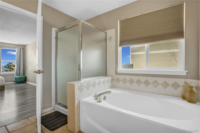 full bath with baseboards, a shower stall, and a garden tub