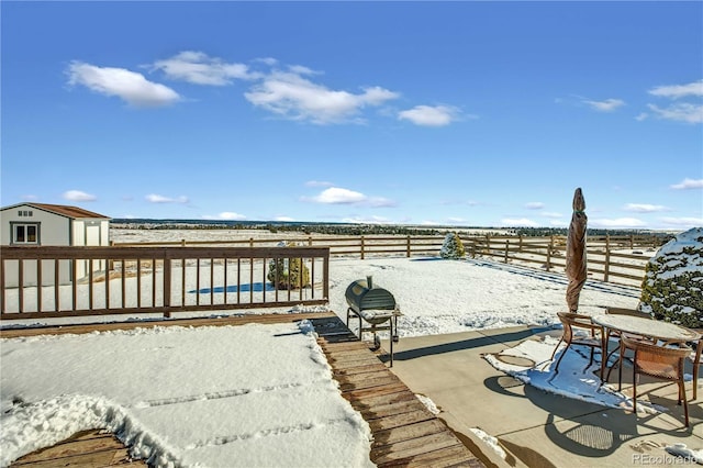 snow covered patio with an outdoor structure and a shed