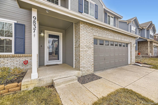 view of exterior entry featuring brick siding, an attached garage, and concrete driveway