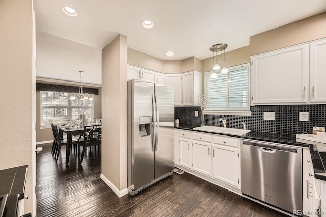 kitchen featuring dark wood-style flooring, a sink, appliances with stainless steel finishes, dark countertops, and backsplash