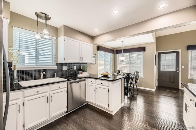 kitchen with dark wood-style floors, a peninsula, a sink, stainless steel dishwasher, and dark countertops