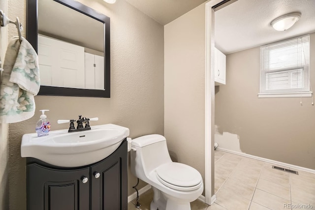 half bath with visible vents, toilet, vanity, and baseboards