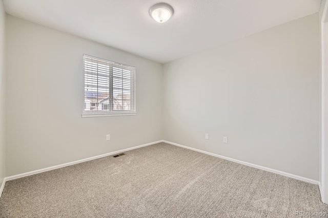 spare room featuring baseboards, visible vents, and carpet floors