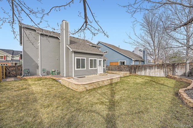 rear view of property featuring roof with shingles, a lawn, a chimney, a fenced backyard, and a patio area