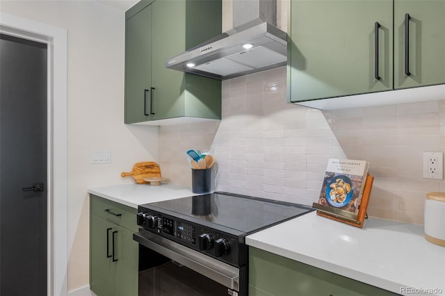 kitchen with decorative backsplash, electric range, wall chimney exhaust hood, and green cabinetry