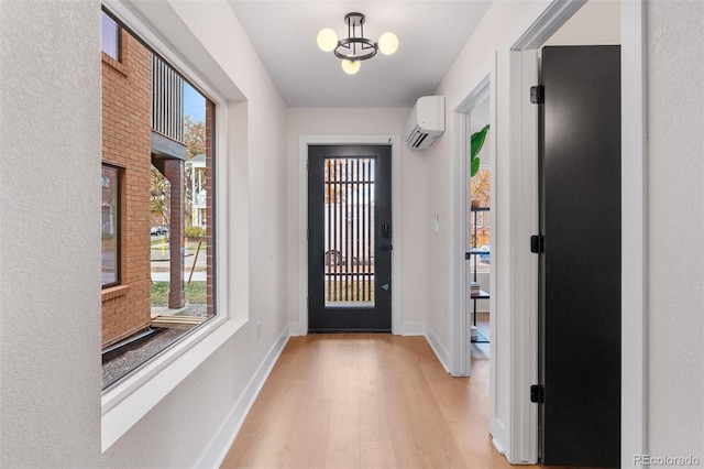 doorway with a wall unit AC, light wood-style flooring, and baseboards