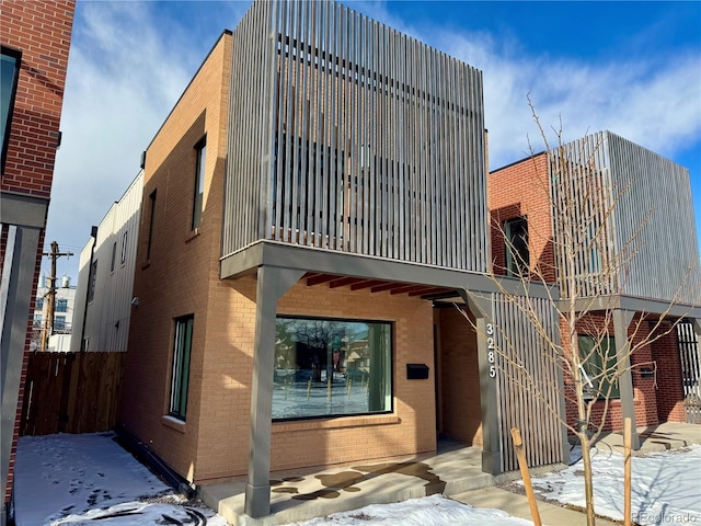 view of snowy property with brick siding