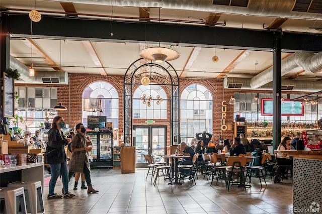 interior space featuring beam ceiling, brick wall, and a high ceiling