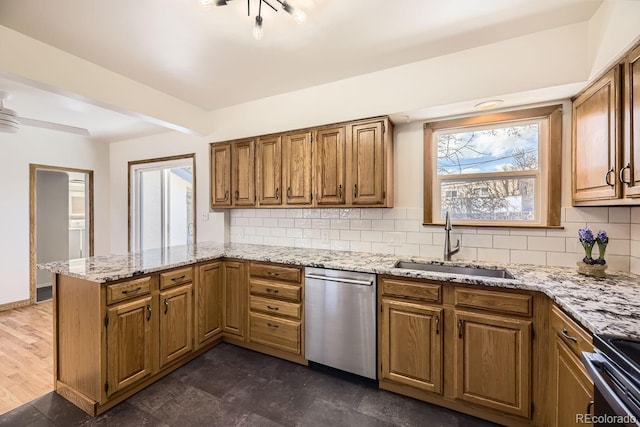 kitchen featuring backsplash, stainless steel dishwasher, a sink, range, and a peninsula