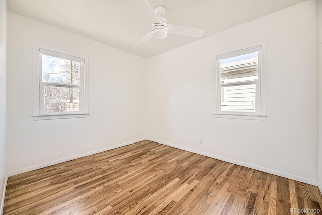 empty room featuring wood finished floors, a ceiling fan, and baseboards