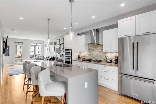 3103 W 18th Ave, Denver, CO 80204 - kitchen with appliances with stainless steel finishes, wall chimney exhaust hood, open floor plan, tasteful backsplash, and recessed lighting