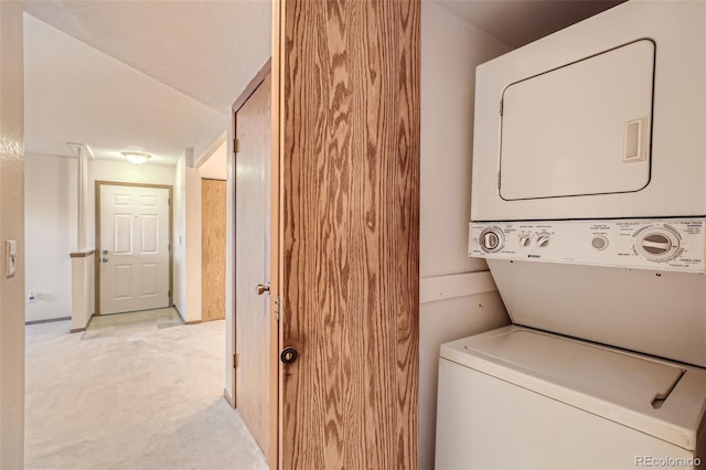 laundry area with light colored carpet and stacked washer / drying machine