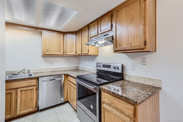 kitchen featuring appliances with stainless steel finishes, dark stone counters, sink, and light tile patterned floors