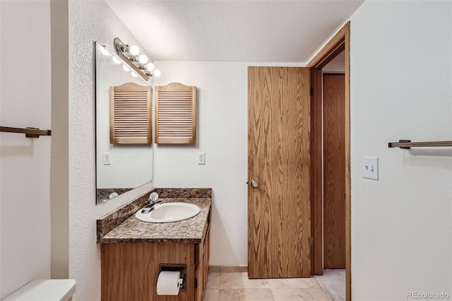 bathroom featuring tile patterned flooring, a textured ceiling, vanity, and toilet