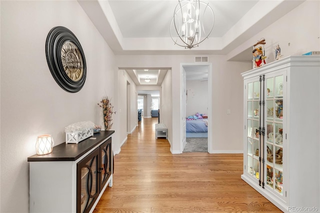 9904 Quintero St, Commerce City, CO 80022 - hallway with a tray ceiling, light wood-style floors, and a chandelier
