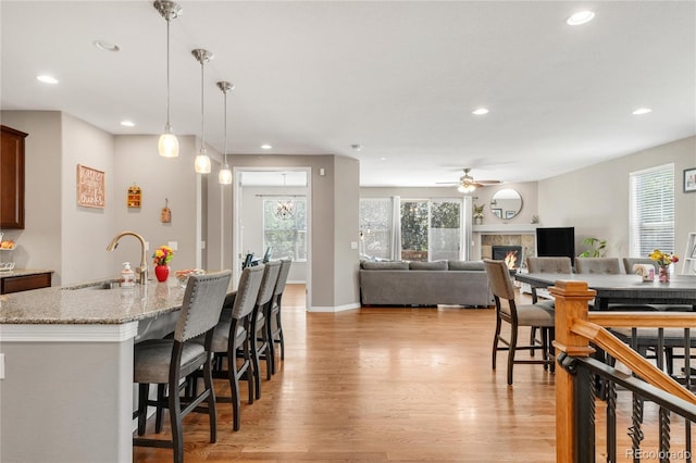 9904 Quintero St, Commerce City, CO 80022 - kitchen with recessed lighting, light wood-type flooring, plenty of natural light, a breakfast bar area, and a tile fireplace