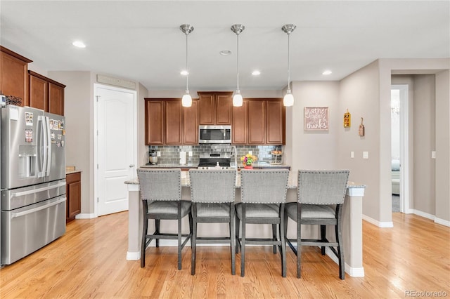 9904 Quintero St, Commerce City, CO 80022 - kitchen featuring stainless steel appliances, light wood-style flooring, decorative backsplash, a kitchen bar, and recessed lighting