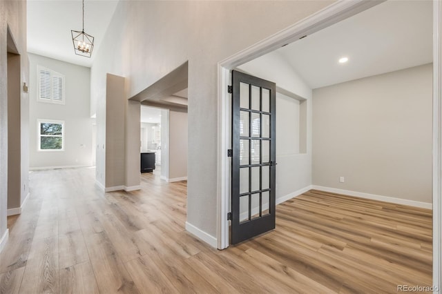 entrance foyer featuring baseboards, an inviting chandelier, and light wood finished floors