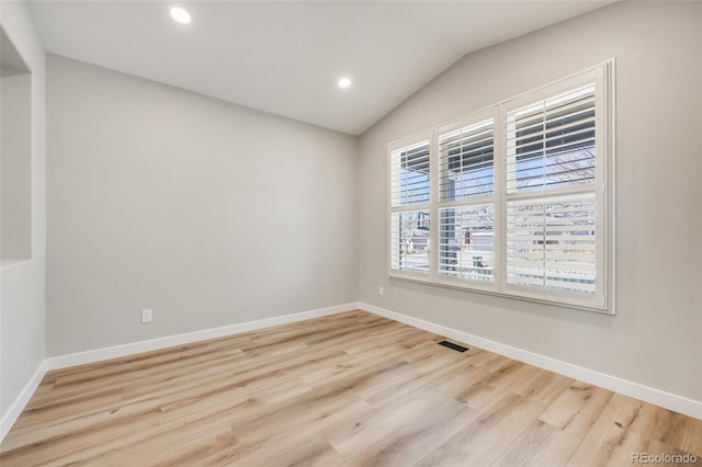 unfurnished room featuring baseboards, lofted ceiling, and wood finished floors