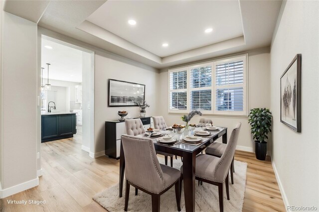 dining space featuring a tray ceiling, recessed lighting, baseboards, and light wood-type flooring