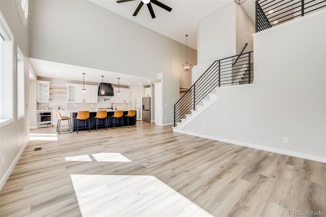 living room with wine cooler, stairway, and light wood-style flooring