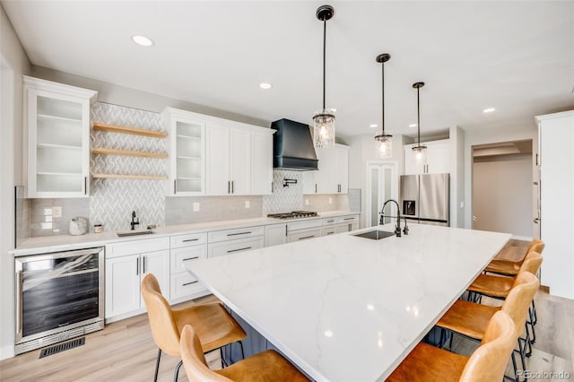 kitchen featuring beverage cooler, a sink, stainless steel appliances, a breakfast bar area, and custom exhaust hood