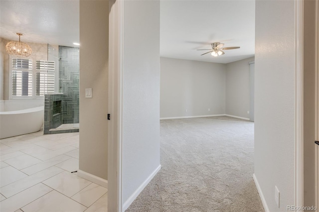 hall featuring a notable chandelier, carpet flooring, and baseboards