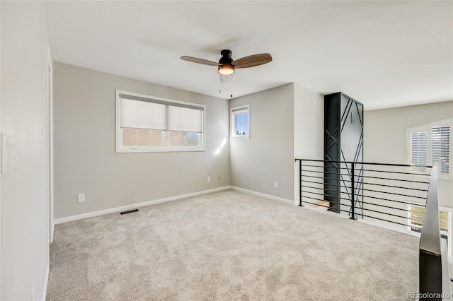 unfurnished room featuring visible vents, carpet floors, baseboards, and a ceiling fan