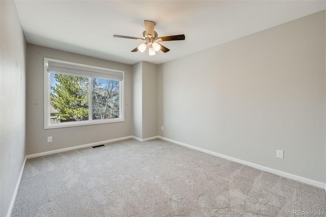 carpeted spare room featuring baseboards, visible vents, and ceiling fan