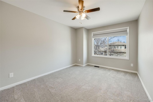 carpeted empty room featuring visible vents, a ceiling fan, and baseboards