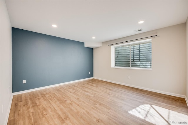 empty room with recessed lighting, wood finished floors, visible vents, and baseboards