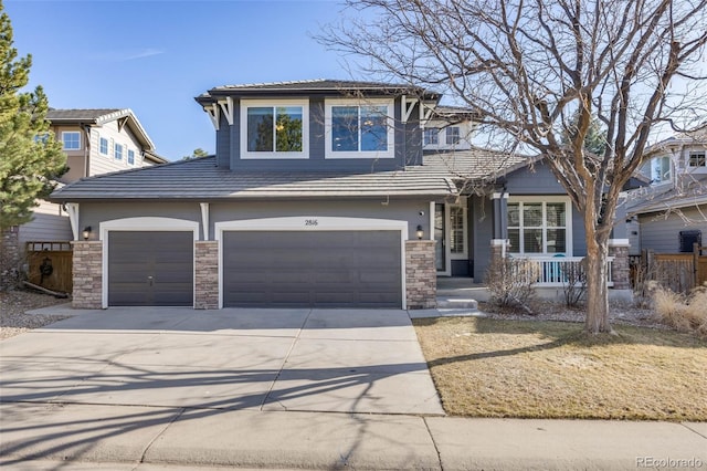 view of front of home featuring stone siding, a tiled roof, and concrete driveway