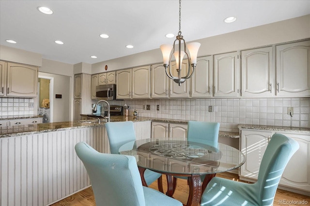 dining space with light hardwood / wood-style floors and an inviting chandelier