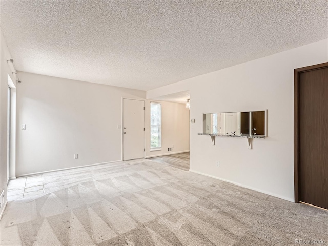 spare room featuring a textured ceiling and light colored carpet