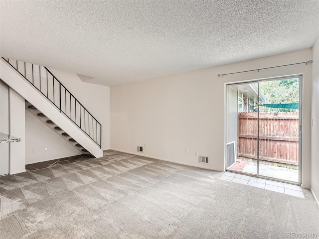 unfurnished living room featuring light carpet and a textured ceiling