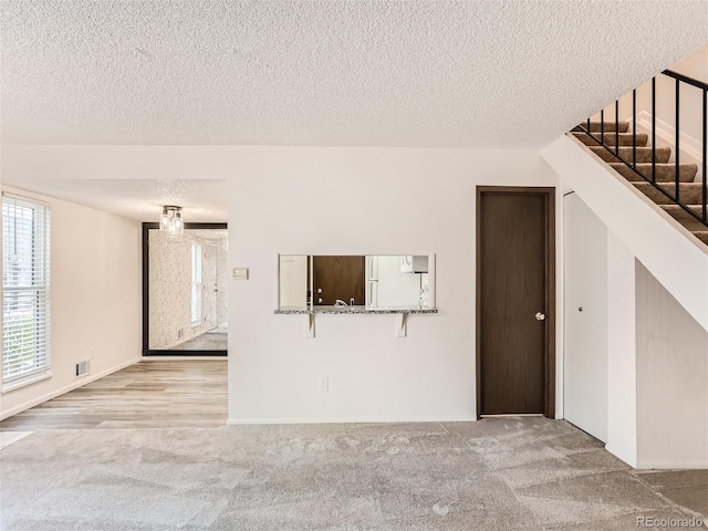 unfurnished living room with light hardwood / wood-style floors and a textured ceiling