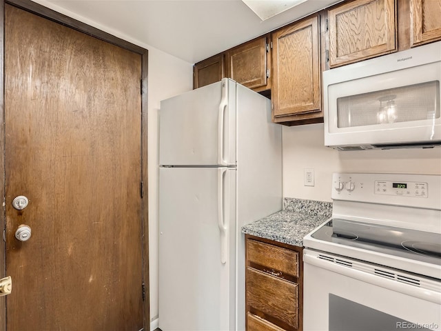 kitchen featuring light stone countertops and white appliances