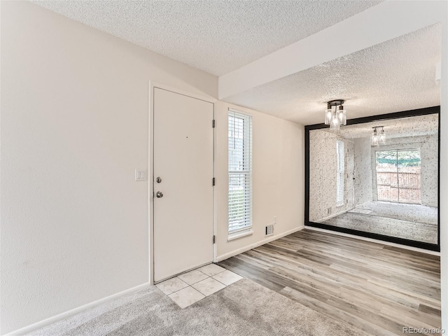 foyer entrance with light hardwood / wood-style floors and a textured ceiling