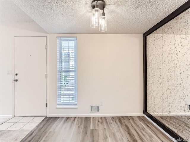 unfurnished room featuring light wood-type flooring and a textured ceiling