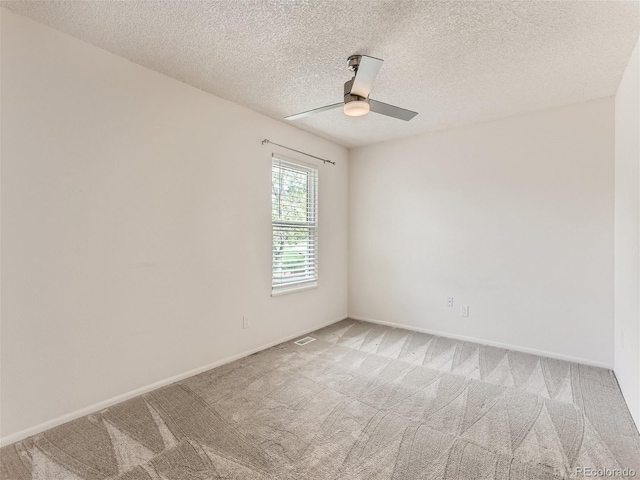 carpeted empty room featuring ceiling fan and a textured ceiling