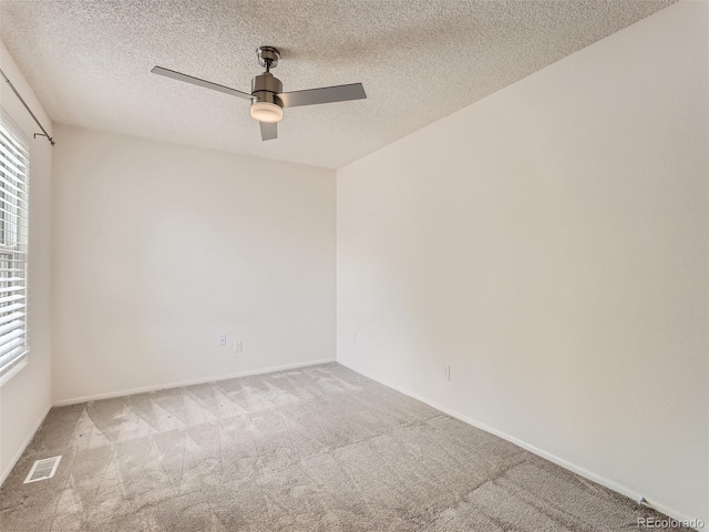 carpeted spare room featuring a textured ceiling and ceiling fan