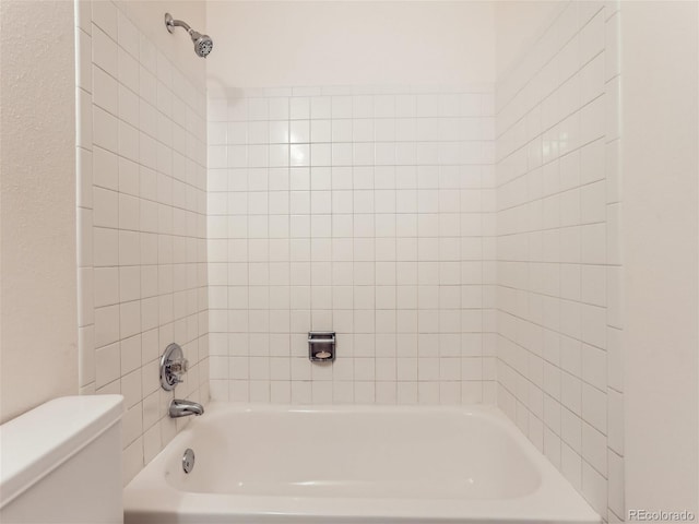 bathroom featuring tiled shower / bath combo and toilet