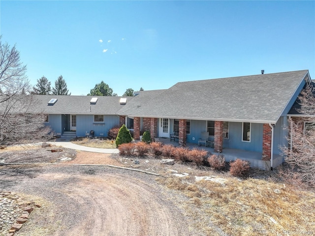 ranch-style house with brick siding, a patio area, driveway, and a shingled roof