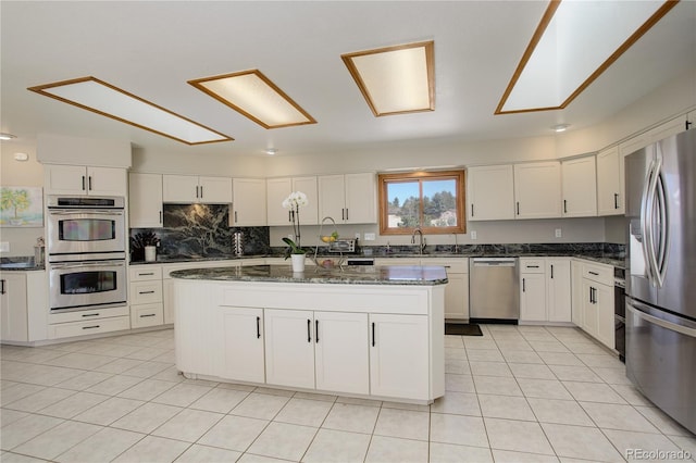 kitchen with light tile patterned floors, appliances with stainless steel finishes, and white cabinetry