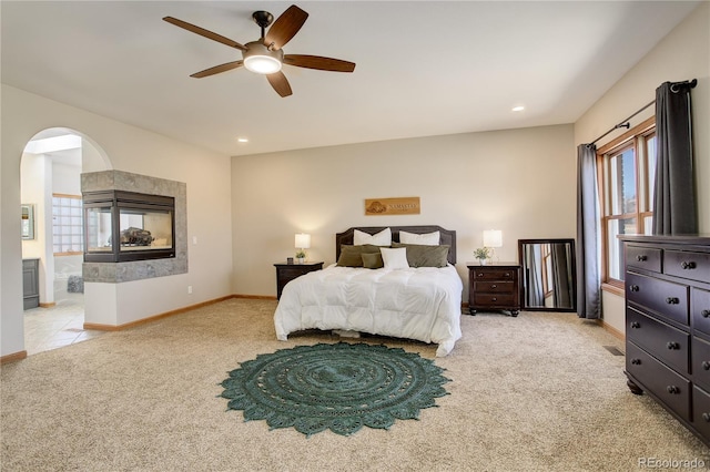 bedroom featuring baseboards, light carpet, recessed lighting, arched walkways, and a ceiling fan