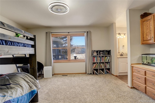 bedroom featuring ensuite bath, light colored carpet, and baseboards