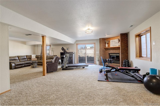 exercise room with carpet flooring, a fireplace, visible vents, and a textured ceiling