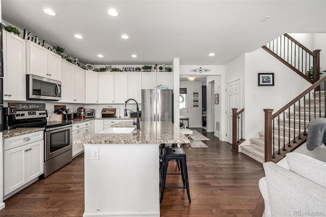 9350 Dunraven St, Arvada, CO 80007 - kitchen featuring appliances with stainless steel finishes, a sink, recessed lighting, a breakfast bar area, and an island with sink