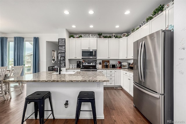 9350 Dunraven St, Arvada, CO 80007 - kitchen featuring stainless steel appliances, a sink, dark wood-style flooring, a breakfast bar, and white cabinets